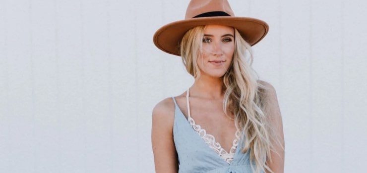 model wearing a tan wide brim hat with denim overalls and a white lace top