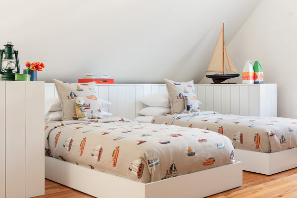 Nautical bedroom interior, two twin beds with Coral and Tusk coastal embroidered pillows and boats fabric duvets.