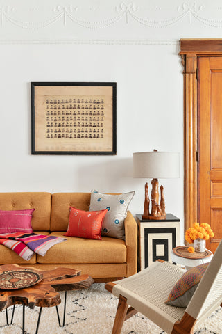 Apartment interior living room, yellow sofa with Coral and Tusk embroidered pillows.