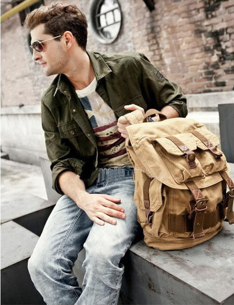 Man holding light brown military travel backpack 