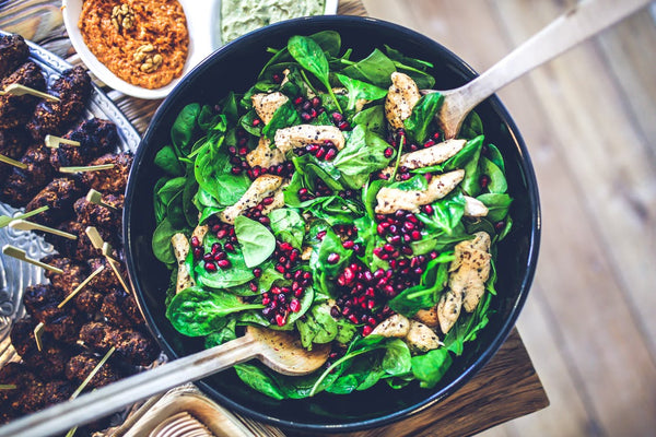 spinach salad with grilled chicken breast and pomegranate sprinkled on top