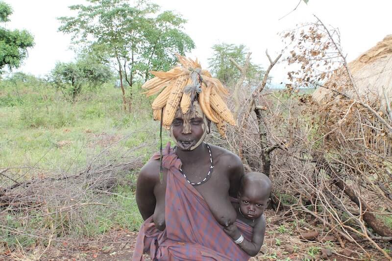 picture of an ethiopian woman and her baby with maize on her head