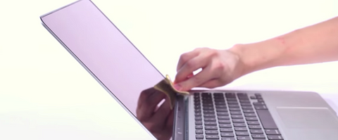 Someone-cleaning-MacBook-screen-with-a-microfiber cloth