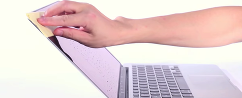 A-person-wipes-the-screen-of a-MacBook-with-a-microfiber-cloth
