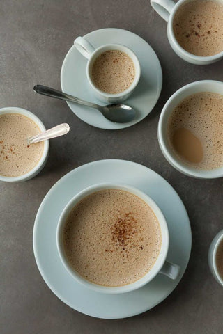 ceramic bowls and mugs of frothy cardamom spiced dandelion root latte