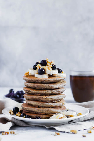 stack of buckwheat pancakes topped with blueberries