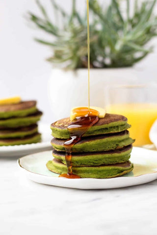 stack of green pancakes with syrup poured from height
