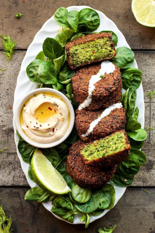 green falafals plated on lettuce leaves halved served with tahini