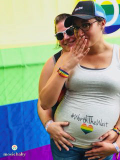 pregnant lesbian couple with a shirt that says "with the wait"
