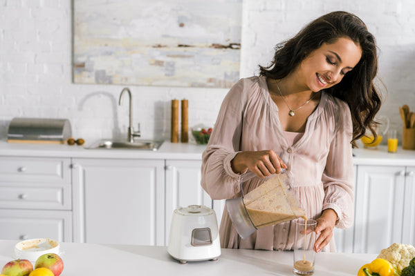 Pregnant woman pouring herself a smoothie