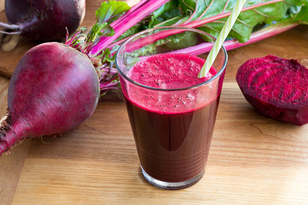 a glass of beet juice as well as some raw beet roots