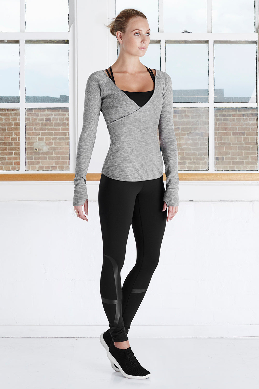 A female dancer in the studio wearing the BLOCH Ladies wrap front top with leggings and active top
