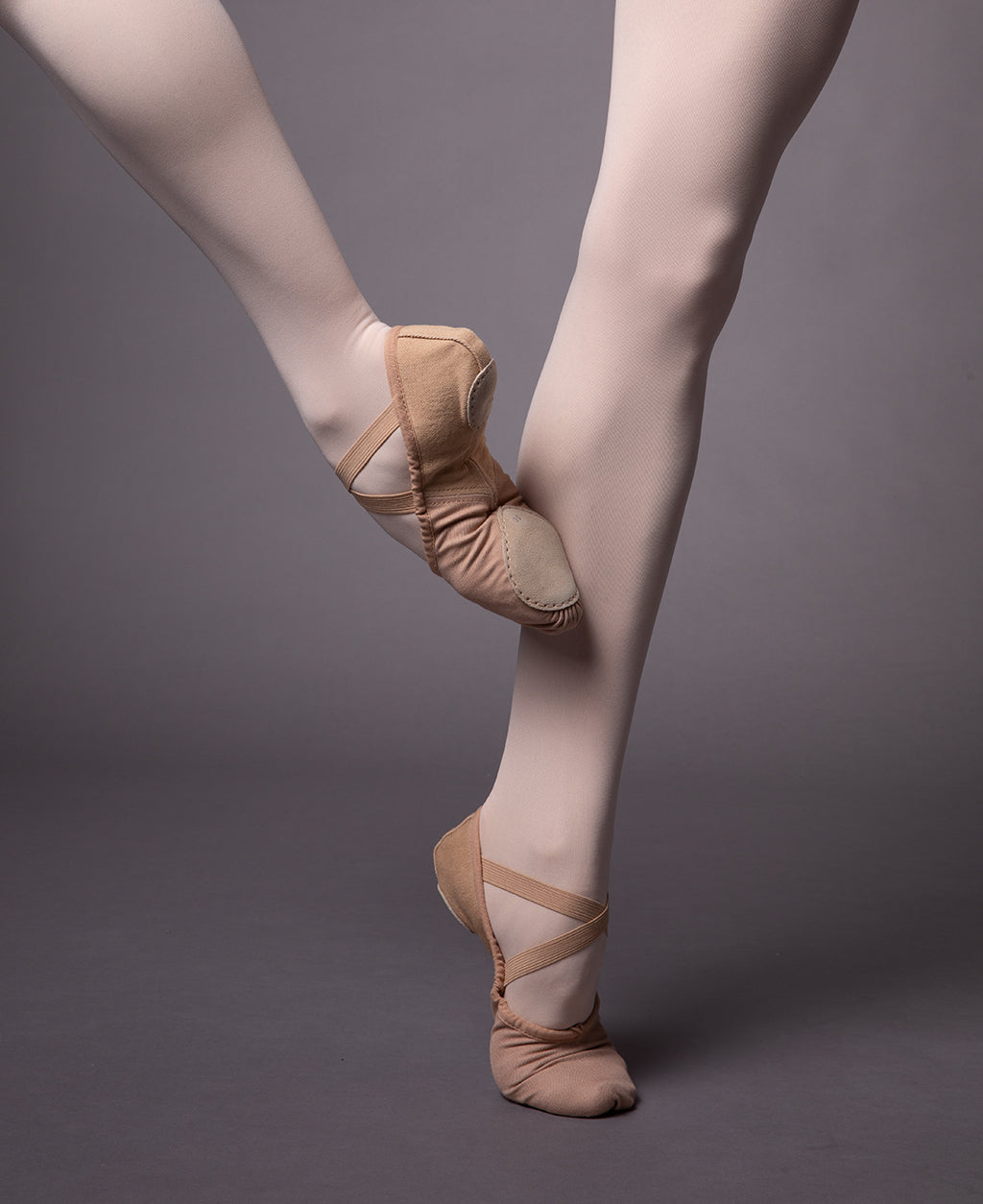 The legs of a dancer wearing the Perfectus ballet flat and pink dance tights 