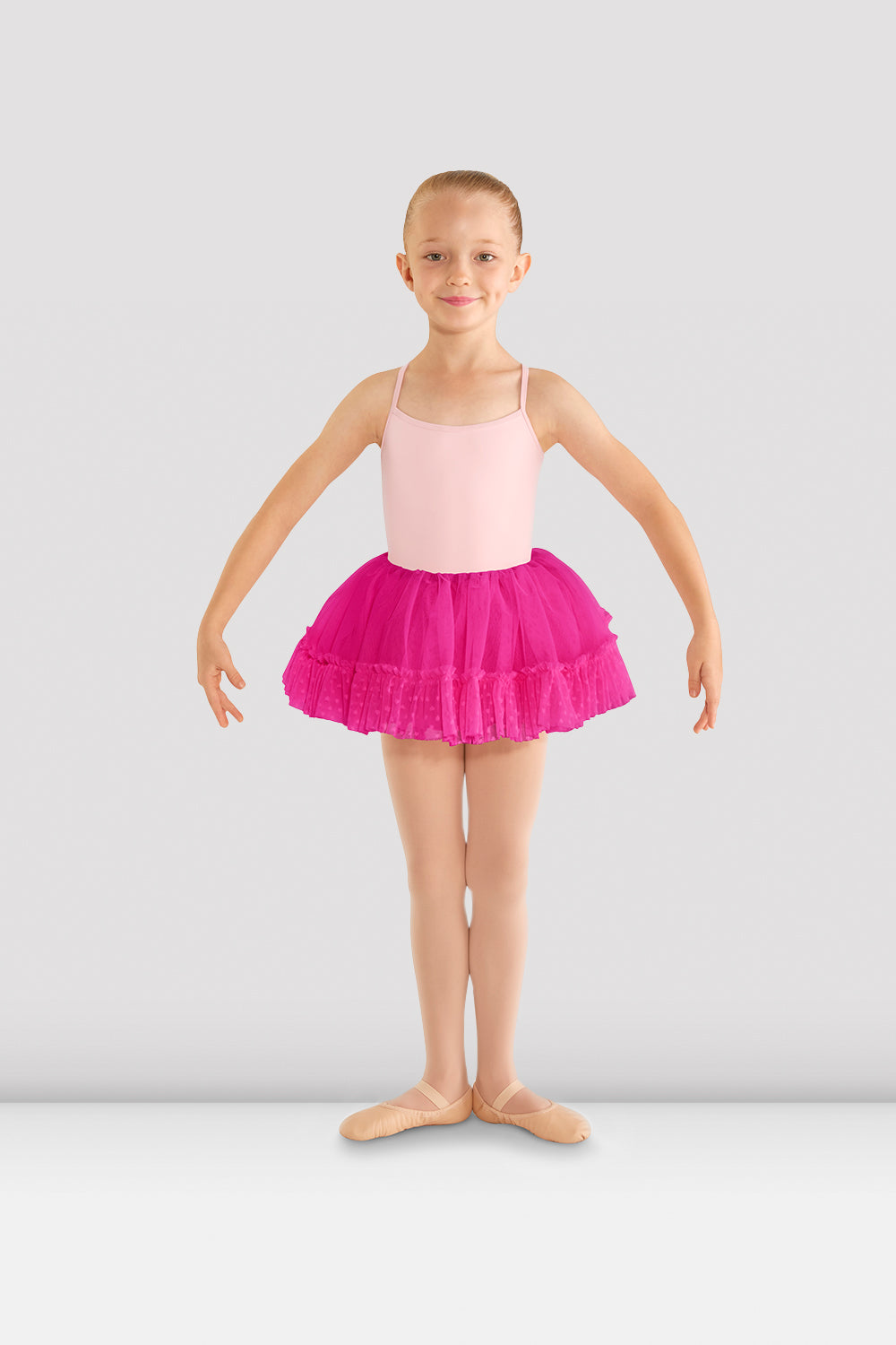 A young female ballet dancer wearing a candy pink camisole leotard with Girls Addelyn heart mesh tutu