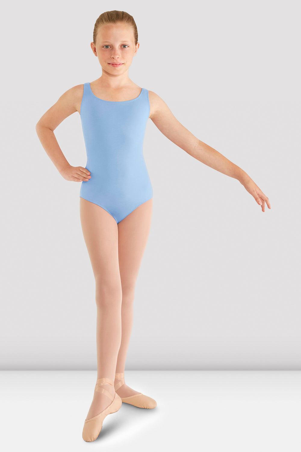 A young ballet dancer pointing her toes wearing the Girls Tank Leotard with support cups in blue