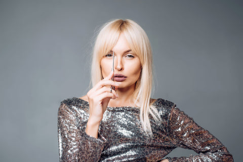 woman with long blonde bangs holding a pair of scissors