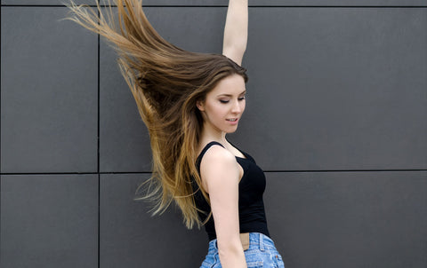 woman flipping her long hair in front of a gray background