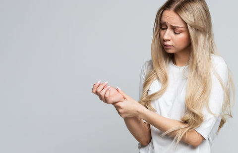 blonde woman holding wrist due to pain from carpal tunnel