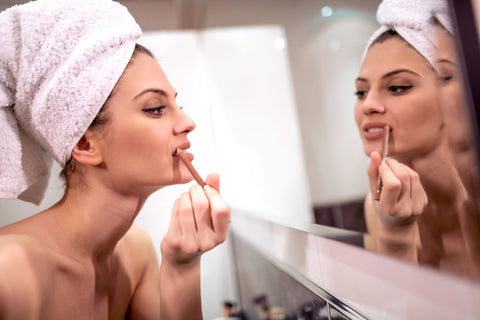 woman applying lip liner in mirror while getting ready for date night