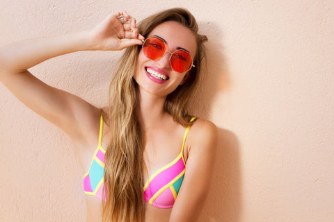 woman in smiling in rose colored sunglasses