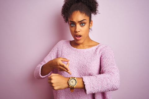 woman in pink pointing to large watch on her wrist