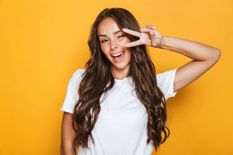 happy woman on yellow background giving a peace sign