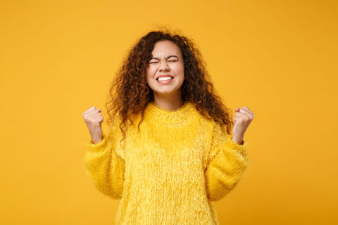 happy woman making a "yes" gesture on orange background