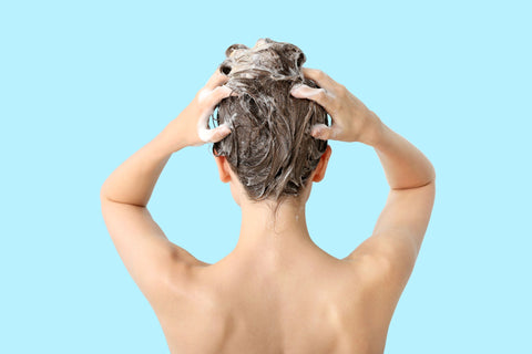 woman shampooing hair on light turquoise background
