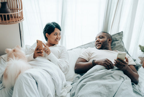 Couple in bed with smart phone in hand