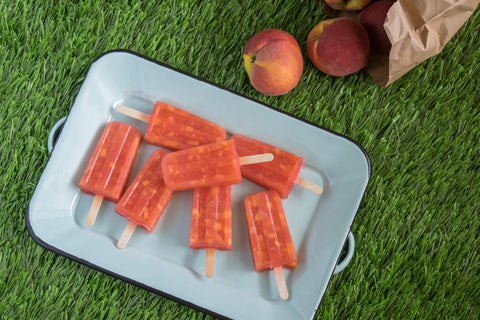 Frozen lemonade peach pops on a tray in grass