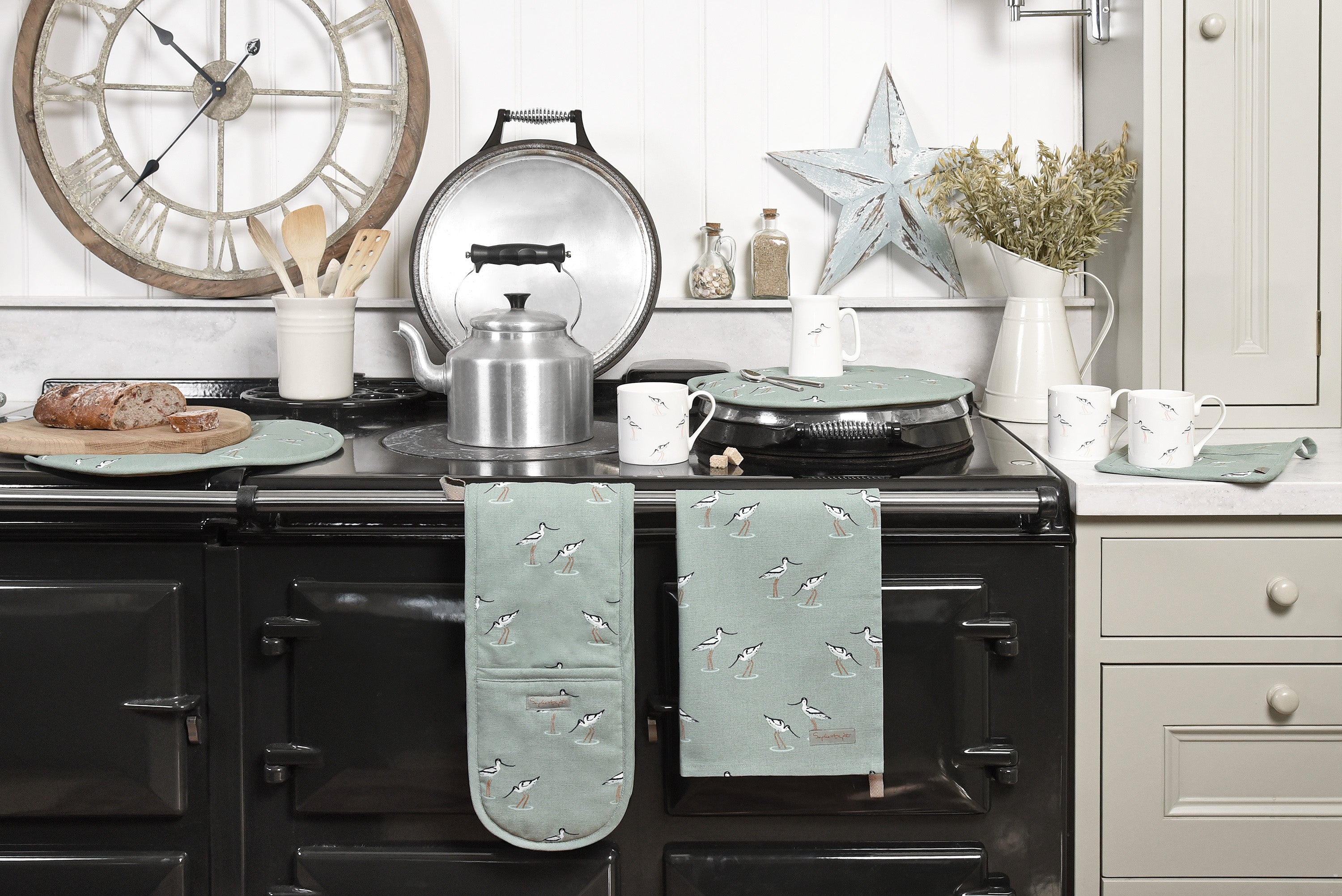 An AGA dressed in Sophie Allport's sea blue green coastal birds collection featuring elegant avocets, including tea towel, oven globes, hob cover, mugs and jugs. 