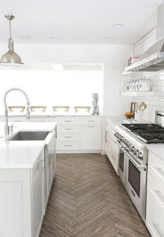 We’re loving the herringbone wood floor and the glossy white tiles of this industrial-inspired kitchen