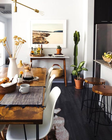 White walls and a black floor, and a hint of glossy bronze textures put the modern in this rustic dining setting. Pendant light over dining table to finish of the look