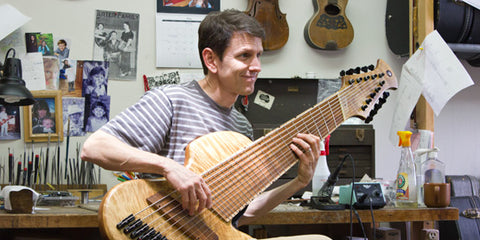 Mike Horan at his bench holding a very, very large bass guitar