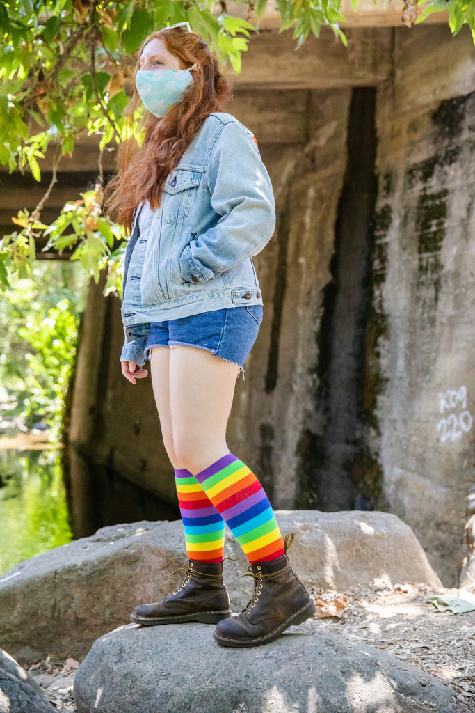 Woman wearing rainbow knee high socks with shorts and boots