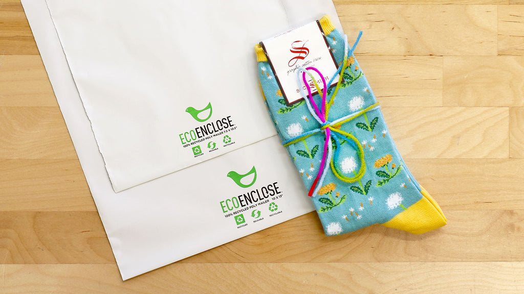 Our eco-friendly shipping bags next to a pair of fun novelty socks