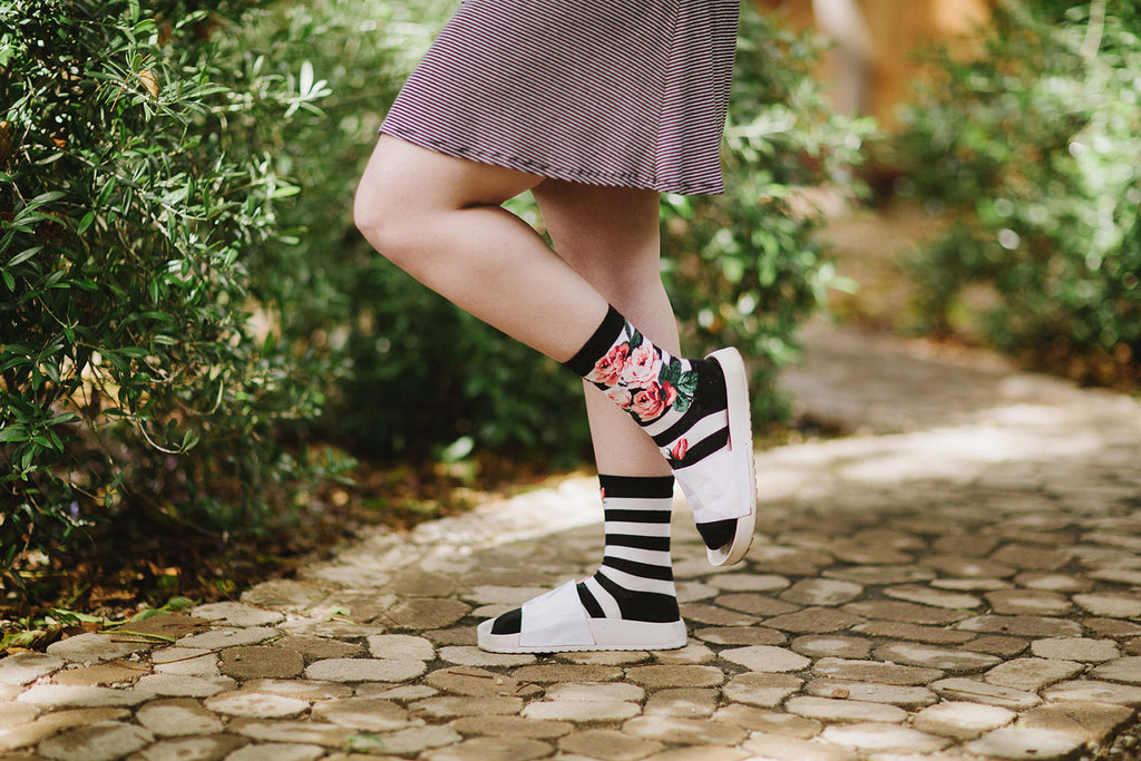 A woman wearing striped rose socks with white sandals