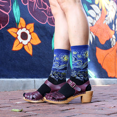 A woman wearing Starry Night art socks with brown leather sandals