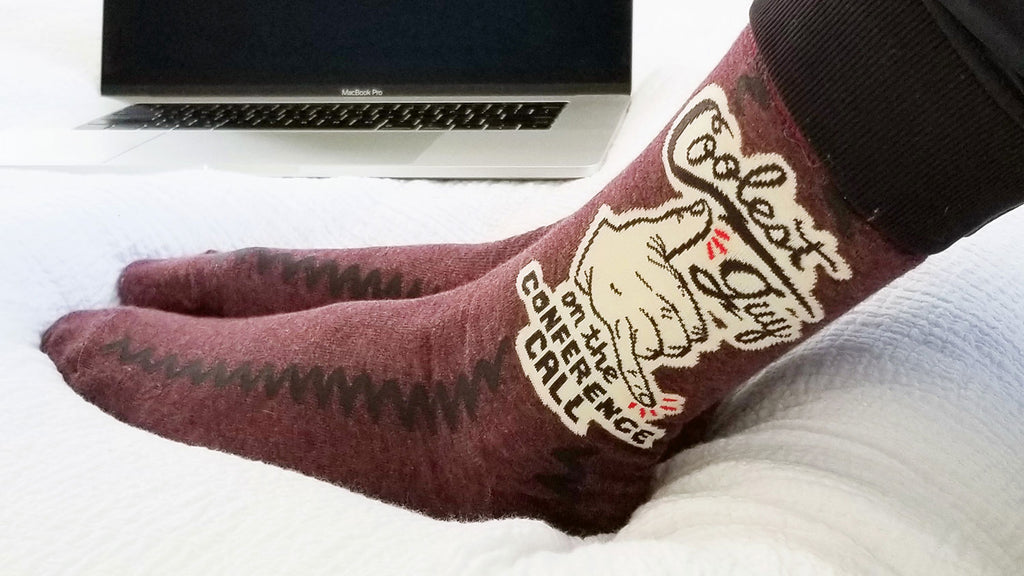 A man wearing funny socks that say, "Coolest guy on the conference call"