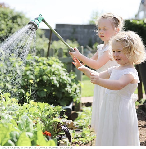 girls watering plants in the garden