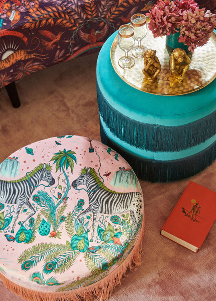 A beautiful pouf covered in the Pink Lost World Velvet featuring curios peacock tailed zebras in an enchanting scene of discovery inspired by the 1925 silent film The Lost World.