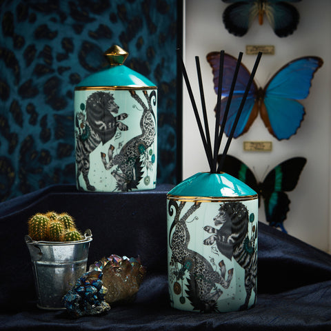 The Caspian Vanilla & Sandalwood scented Candle and Diffuser featuring the the iconic British lion and unicorn, inspired by C.S.Lewis’ world of Narnia, with details of surreal trees that add a signature twist to this design. On the Right - The Kruger Aromatic Woods Scented Candle and Diffuser inspired by an African safari adventure and features a fantastical array of creatures and foliage, including spotted giraffes sheltering under tropical palms. 