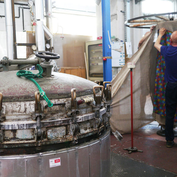 Left: Fabrics are hung up for steaming after printing. Right: The piece being held has already been steamed - showing the difference it makes in bringing out the rich and vibrant colours.