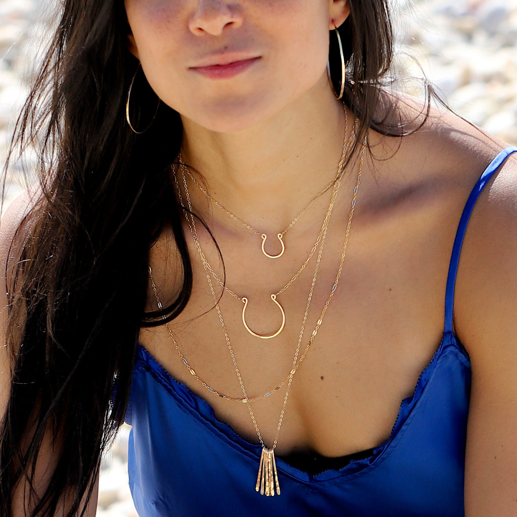 girl with blue shirt in layered long delicate gold necklaces