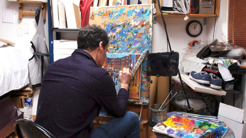 Artist Chris McMorrow working on a painting on an easel in his studio