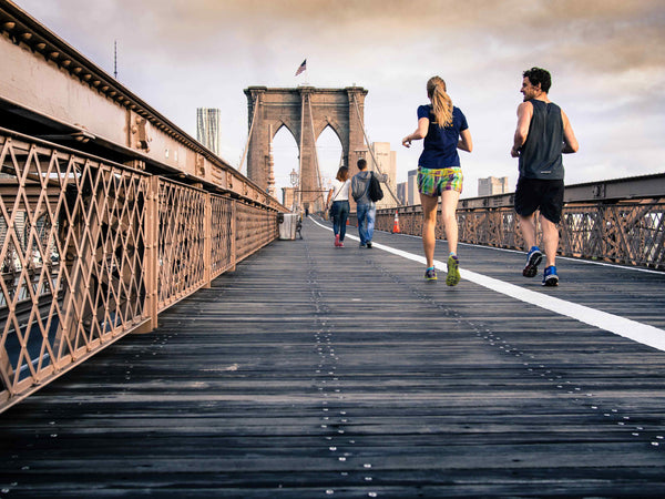 man and woman jogging on a bridge