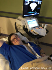 Wearing a blue AudreySpirit shirt unsnapped down the front, but covering her breasts, Ellie gets an ultrasound image to recheck her heart's function at Children's Mercy Hospital