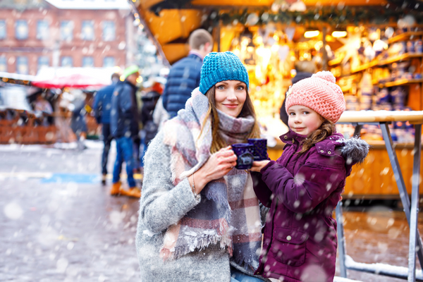 Une maman et sa fille se réchauffant en dégustant un chocolat chaud pendant un .marché de Noël