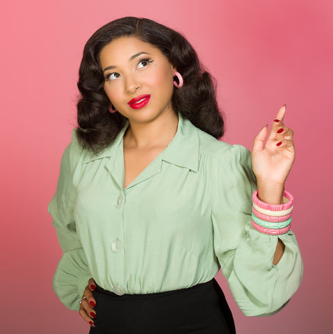 Eva Leigh wearing a selection of fakelite jewellery against a pink background