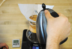 Someone pouring boiling water into Chemex brewer